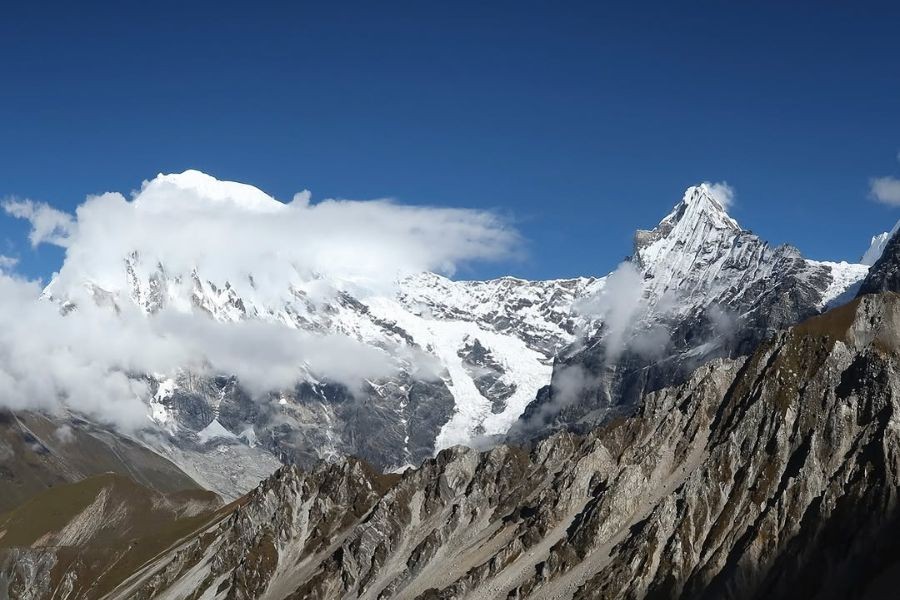 Snow-covered Langtang Lirung peak with dramatic clouds and rocky mountain ridges